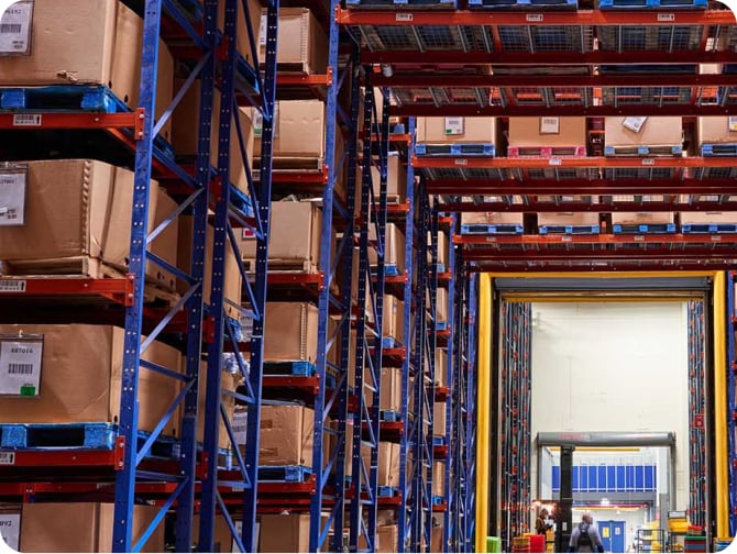 Amplio almacén industrial con techos altos y estanterías de inventario perfectamente organizadas, que muestran pasillos despejados y abundante almacenamiento.